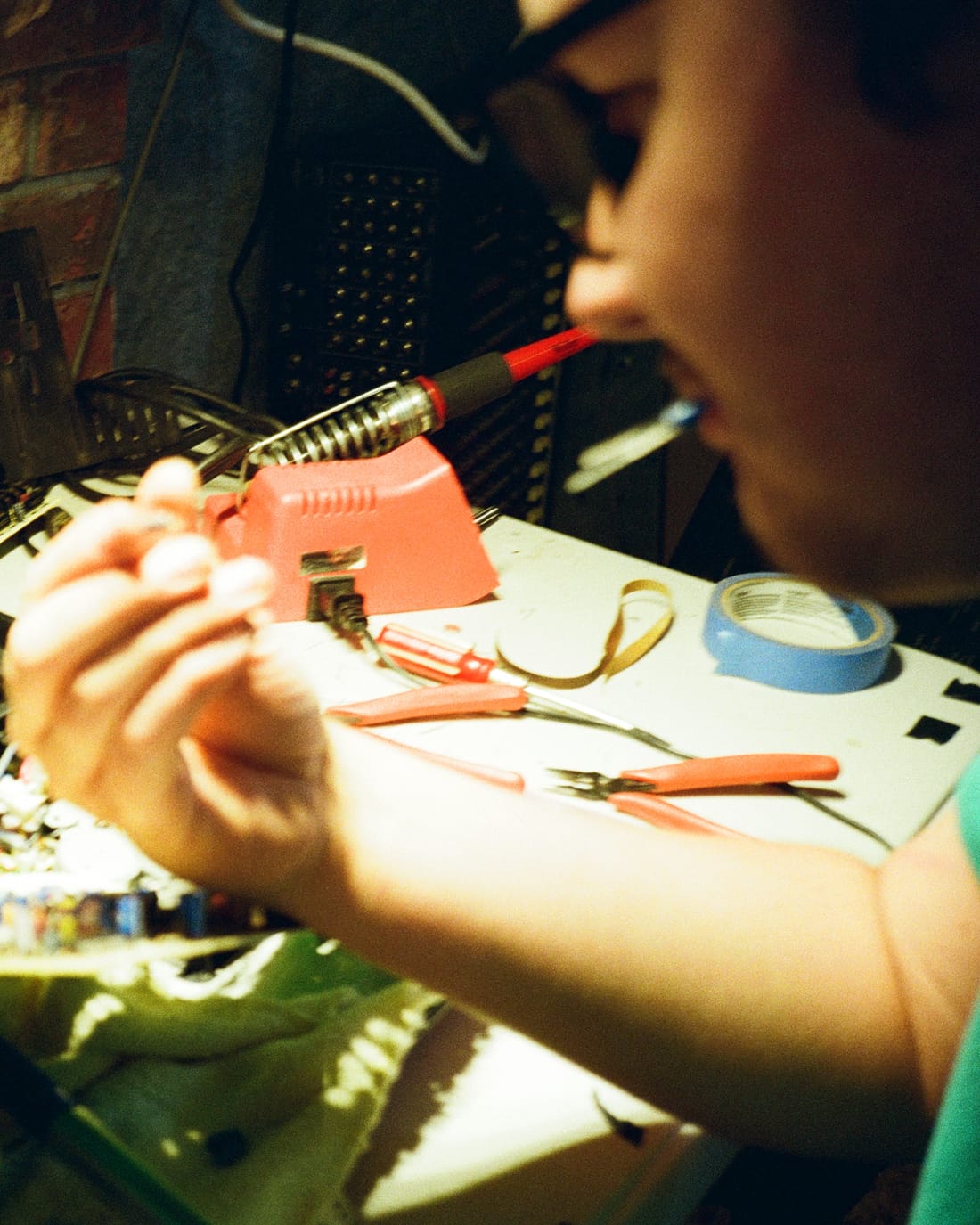 Soldering a circuit board at the workbench, boards and tools spread across the table